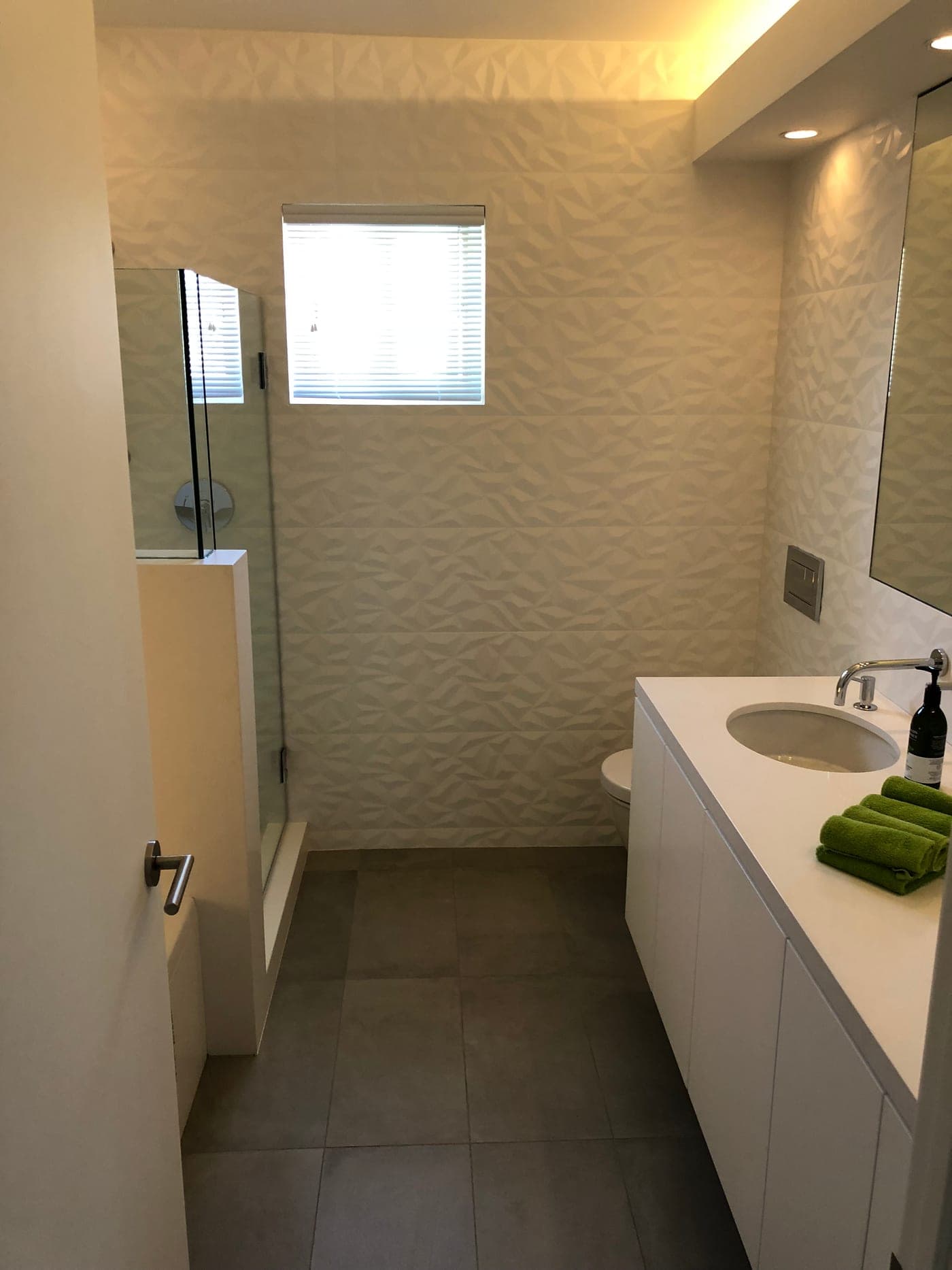 Beverly Hills bathroom by Accelerate Construction with a sculptural 3D-tile feature wall, a white floating vanity and cove lighting