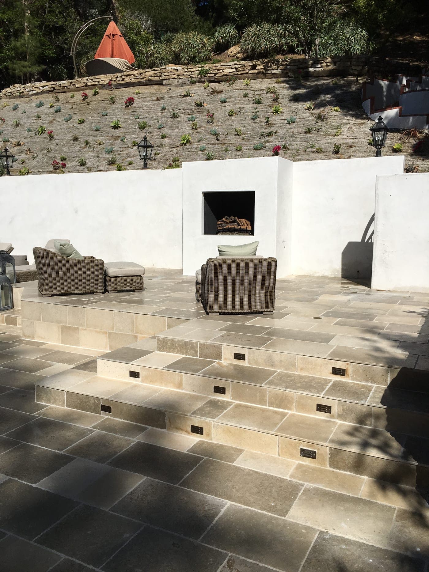 Beverly Hills backyard with a stone-paved patio and a built-in outdoor fireplace in a smooth stucco wall
