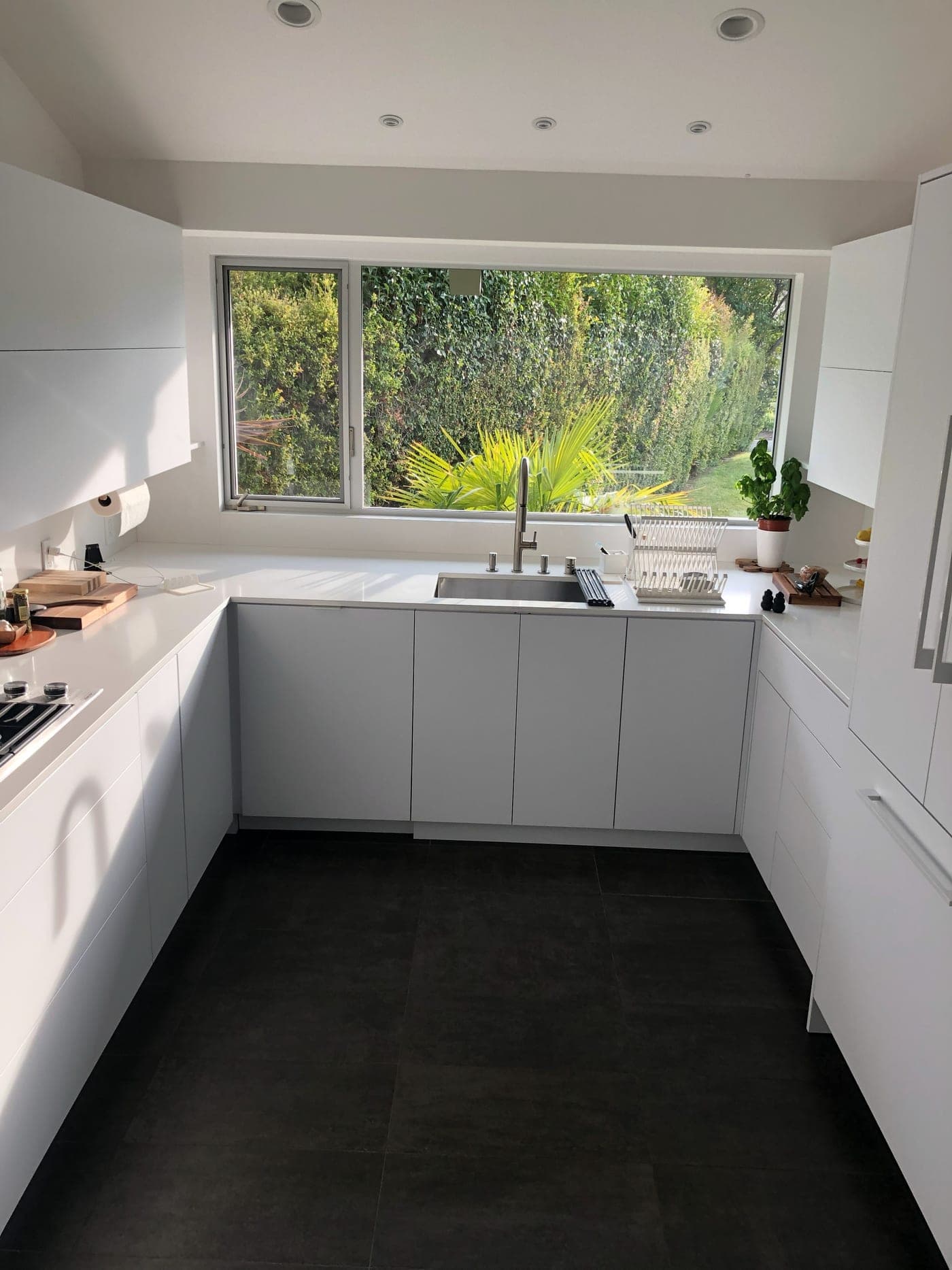 Los Angeles kitchen by Accelerate Construction with handleless white cabinetry, quartz counters and a picture window