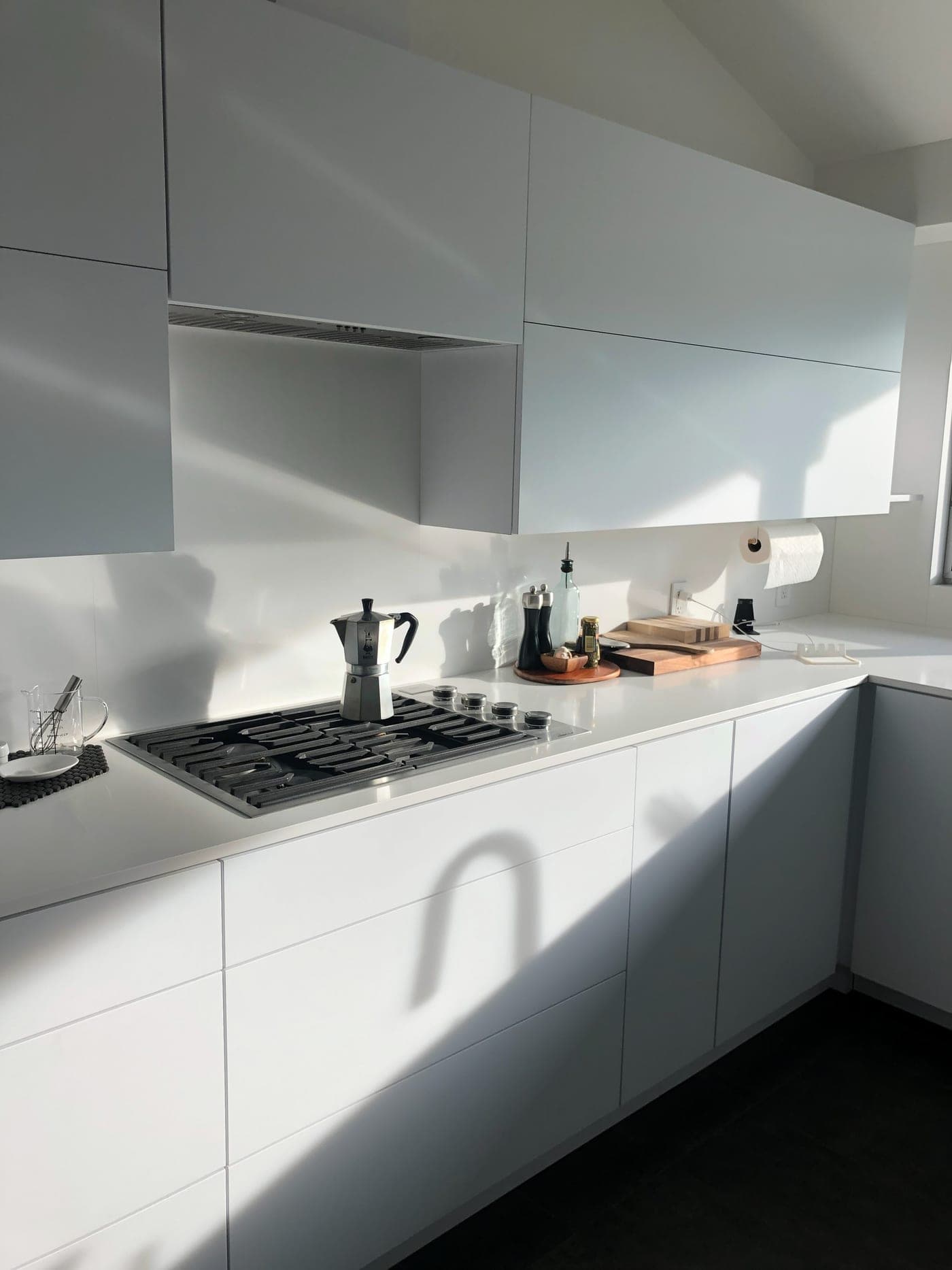 Los Angeles kitchen by Accelerate Construction with handleless white cabinetry, a gas cooktop and a white slab backsplash