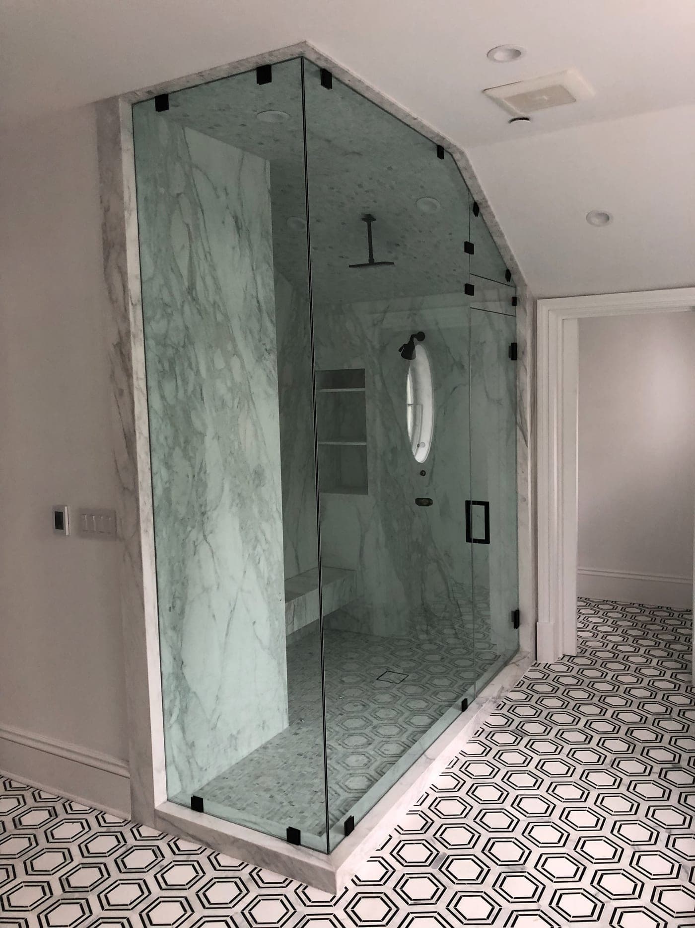 Pacific Palisades bathroom by Accelerate Construction with a frameless glass steam shower in book-matched Calacatta marble under a sloped dormer ceiling
