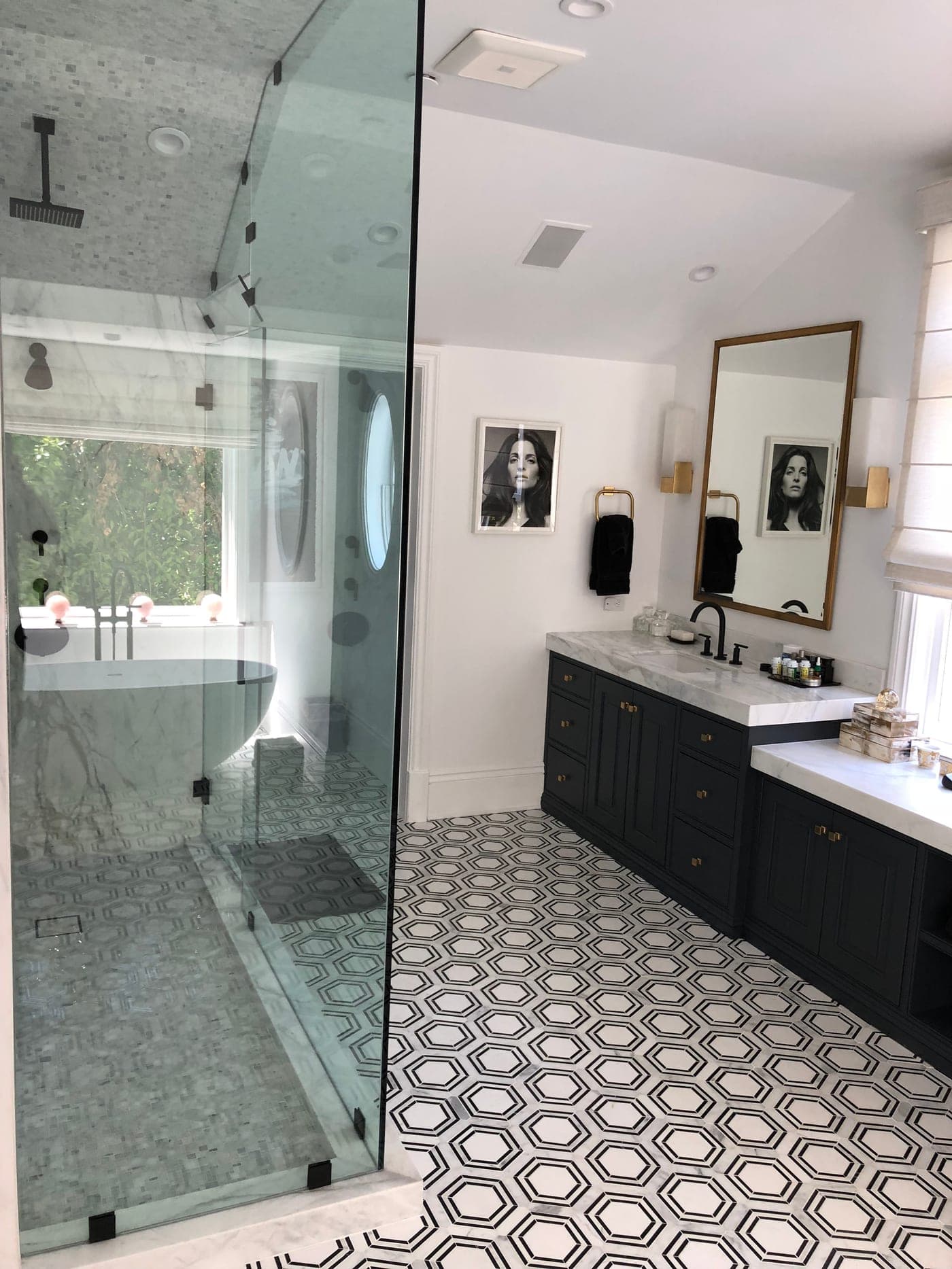 Pacific Palisades primary bathroom by Accelerate Construction with a navy double vanity, marble counters, a frameless glass shower and a black-and-white hex-tile floor