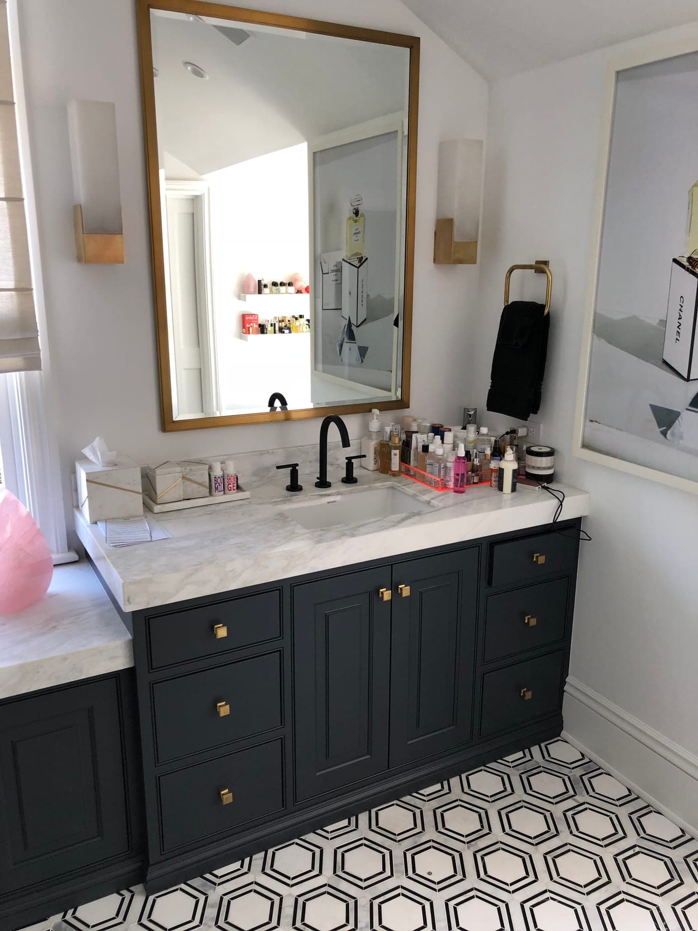 Navy vanity with marble counter, brass hardware, an antique-brass mirror and sconce in a Pacific Palisades bathroom by Accelerate Construction