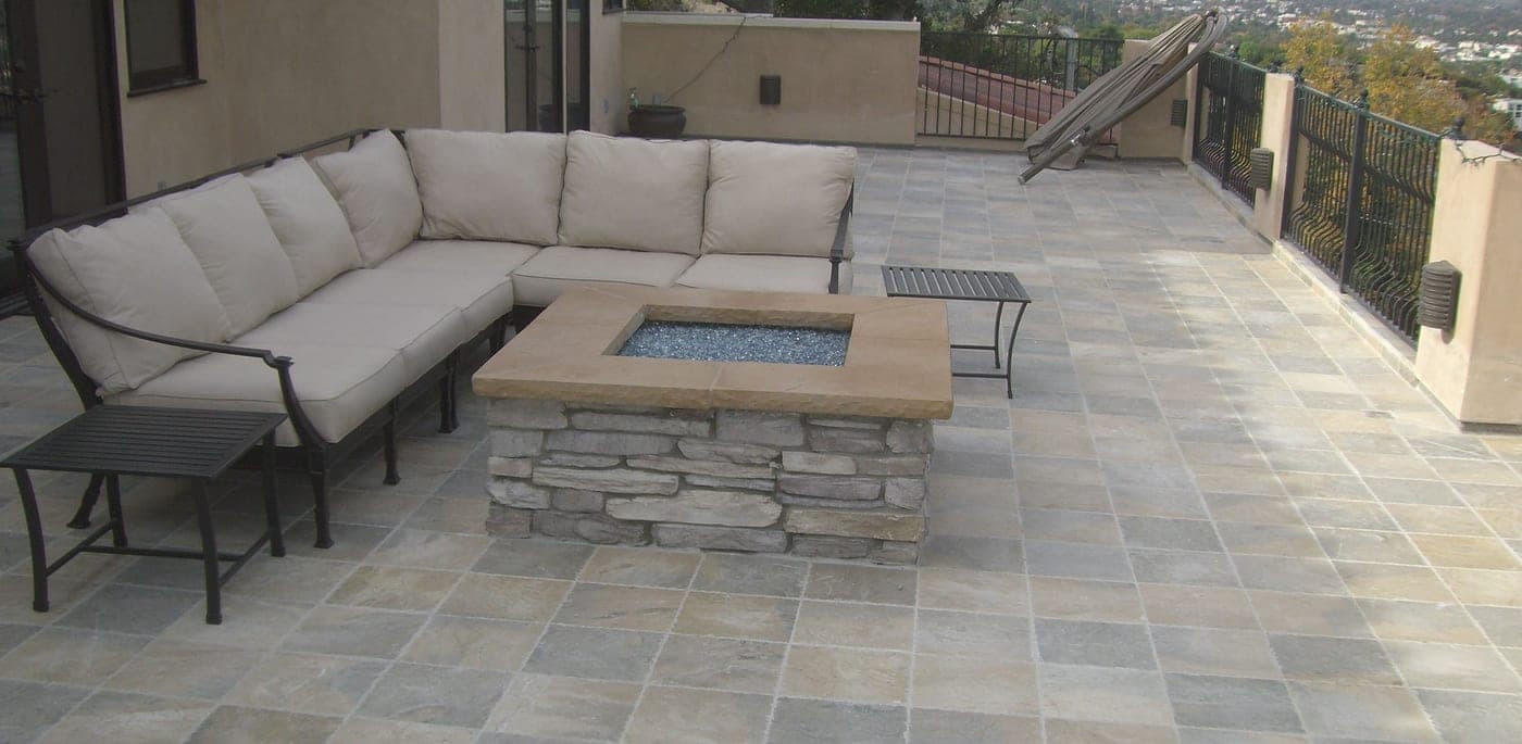 The repaired Studio City rooftop deck with fresh stone tile and a custom stone gas firepit