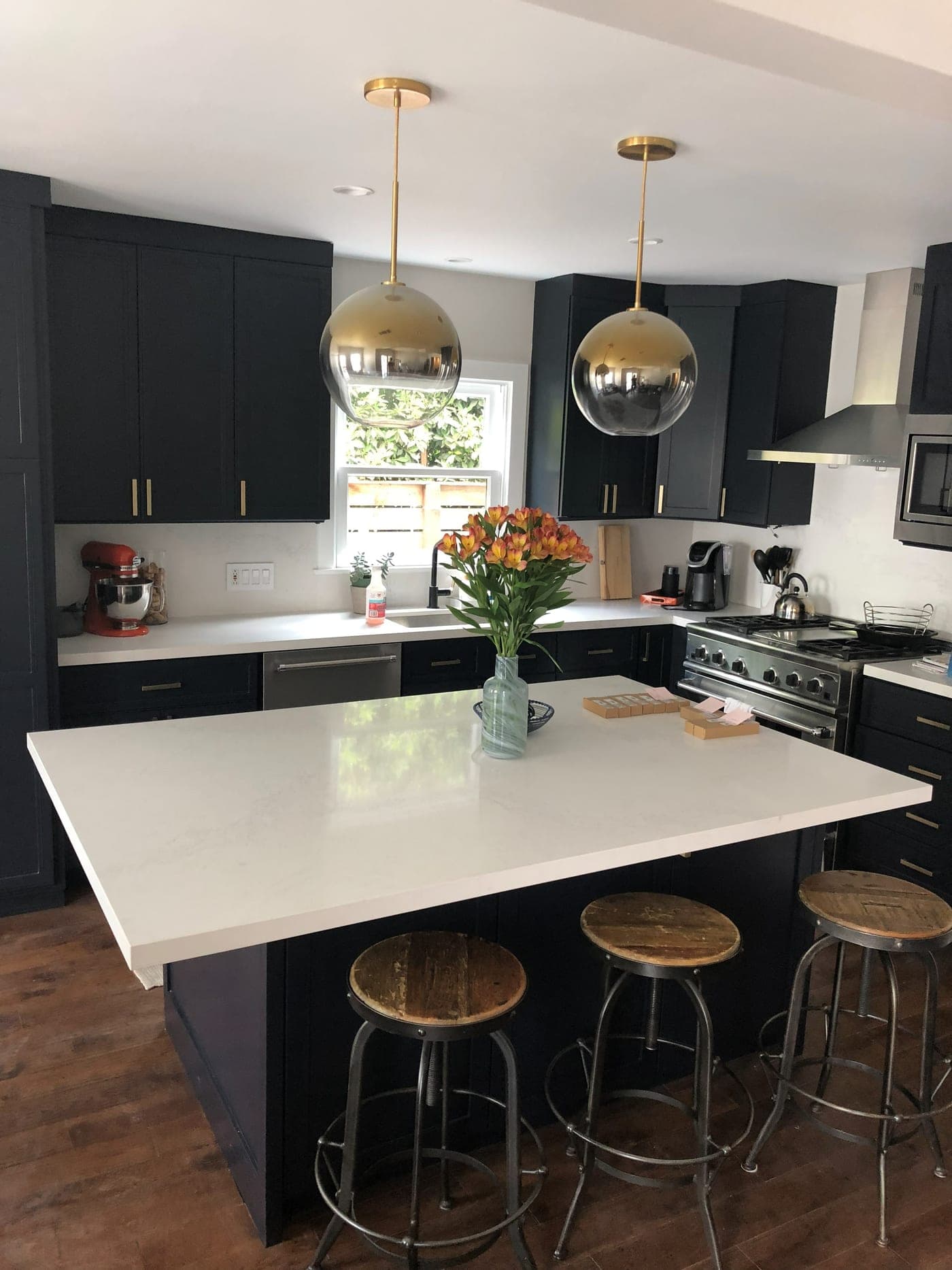 West Hollywood kitchen by Accelerate Construction with navy shaker cabinetry, a white quartz island with seating and globe pendants