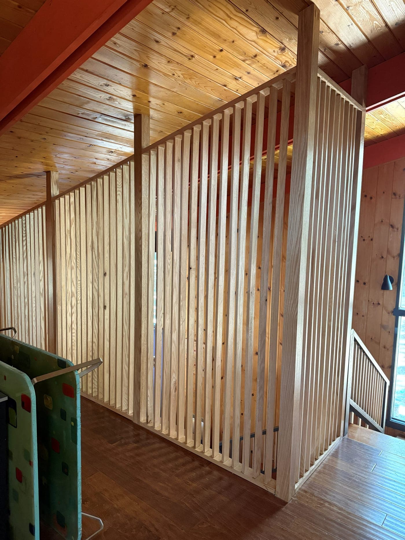 Custom wood slat railings around the stair opening in the renovated Wrightwood home, under the pine-plank ceiling