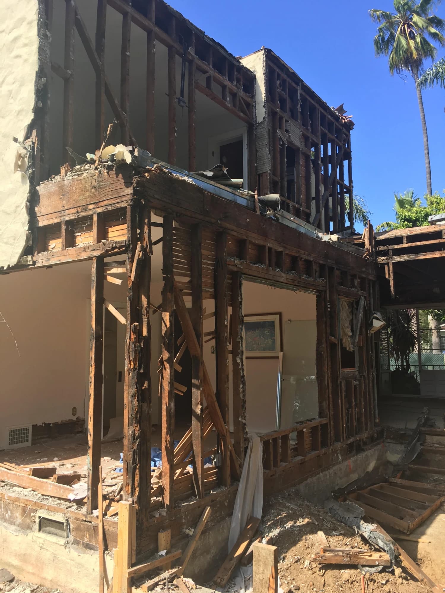 Selective demolition of a two-story stucco home, its exterior walls opened to the original framing and lath